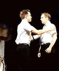 Two Men Are Standing Next To Each Other On A Stage And Hugging Each Other . GIF