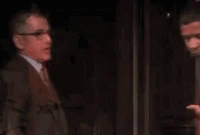 Two Men Are Standing Next To Each Other On A Stage In A Dark Room . GIF