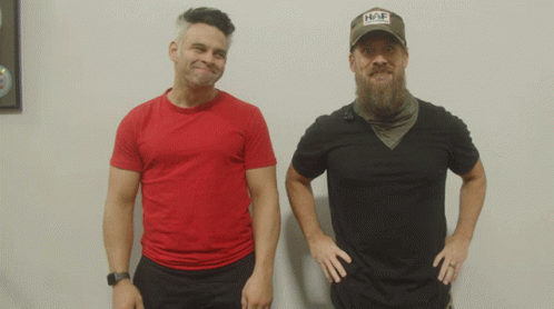 Two Men Are Standing Next To Each Other One Wearing A Hat That Says Hap GIF