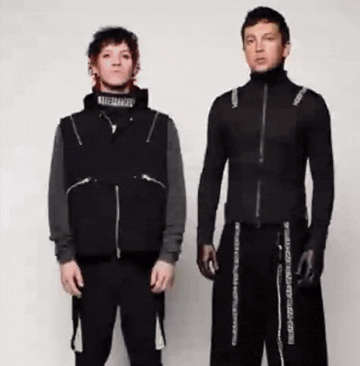 Two Men Are Standing Next To Each Other Wearing Black Clothes And Gloves . GIF