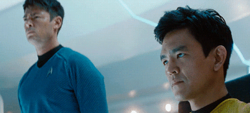 Two Men Are Standing Next To Each Other With One Wearing A Blue Shirt With The Letter A On It GIF