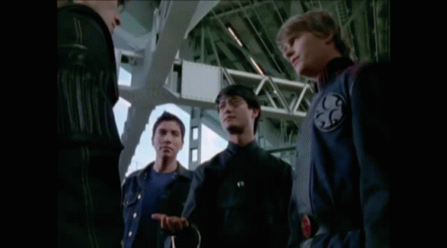 Two Men Are Standing Next To Each Other With One Wearing A Watch That Has A Red Circle On It GIF