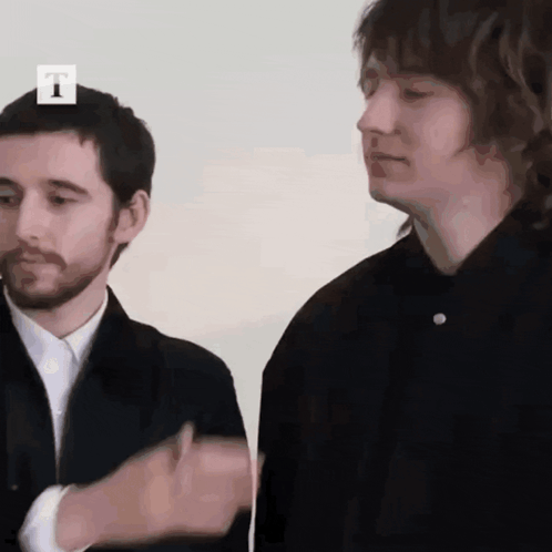 Two Men Are Standing Next To Each Other With The Letter T On The Top GIF