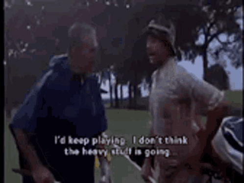 Two Men Are Standing On A Golf Course Talking To Each Other . One Of The Men Is Holding A Golf Club . GIF