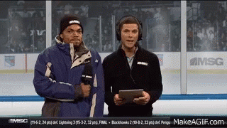 Two Men Are Standing On A Hockey Rink Talking Into Microphones . GIF