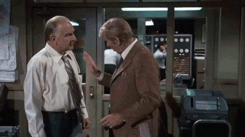 Two Men Are Talking In Front Of A Door That Says Rio GIF