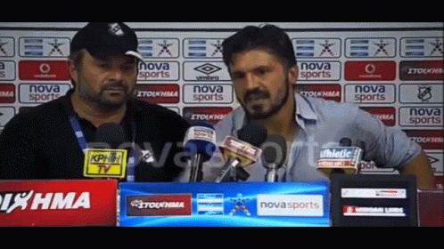 Two Men Are Talking In Front Of A Nova Sports Banner GIF