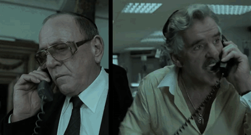 Two Men Are Talking On Their Phones And One Has Glasses On GIF