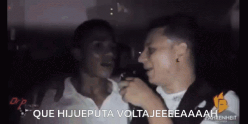 Two Men Are Talking To Each Other In A Dark Room And The Words Que Hijueputa Voltajeeeaaaah Are On The Screen GIF