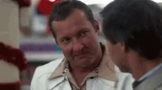 Two Men Are Talking To Each Other In A Store And One Of Them Is Making A Funny Face . GIF