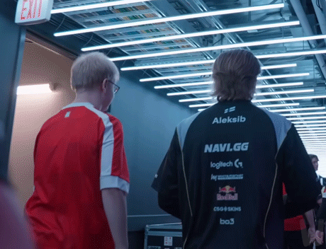 Two Men Are Walking Down A Hallway And One Of Them Is Wearing An Aleksib Navi.gg Jacket GIF