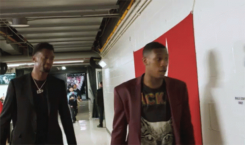 Two Men Are Walking Down A Hallway With A Sign That Says Bulls Staff Only On It GIF
