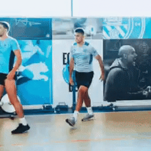 Two Men Are Walking On A Basketball Court In Front Of A Wall That Says Ec On It GIF