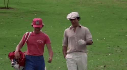 Two Men Are Walking On A Golf Course And One Of Them Is Wearing A Pink Shirt That Says Columbia GIF