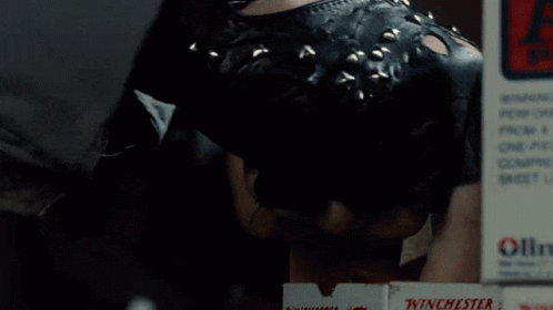 Two Men Are Working In A Gun Shop With An Exit Sign Above Them GIF
