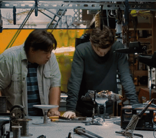 Two Men Are Working On A Project In A Workshop With A Soldering Iron That Says ' A ' On It GIF