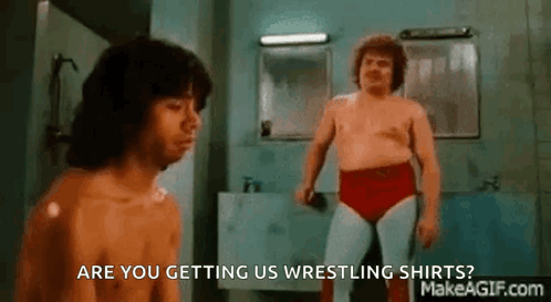 Two Men Are Wrestling In A Bathroom And One Of Them Is Asking If They Are Getting Us Wrestling Shirts . GIF