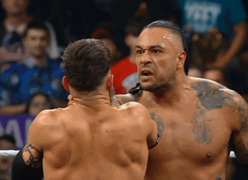 Two Men Are Wrestling In A Ring And One Of Them Has A Tattoo On His Arm GIF