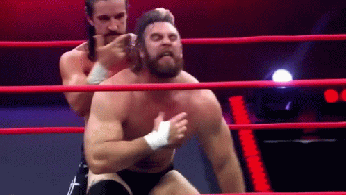 two men are wrestling in a ring and one of them is wearing a bandage on his chest .