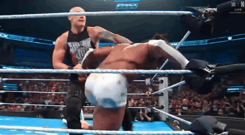 Two Men Are Wrestling In A Ring And One Of Them Is Wearing A Tank Top That Says Smack Down GIF