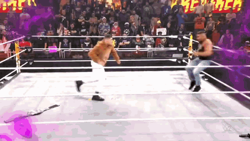 two men are wrestling in a ring with a crowd in the background