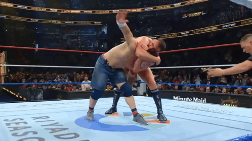 Two Men Are Wrestling In A Ring With A Minute Maid Advertisement On The Side GIF