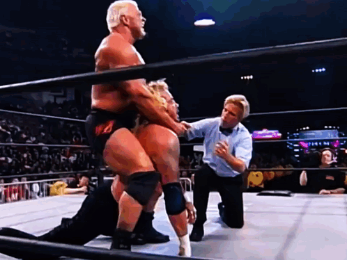 Two Men Are Wrestling In A Ring With A Referee GIF