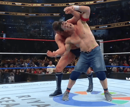 Two Men Are Wrestling In A Ring With A Sign That Says ' Sea ' On It GIF