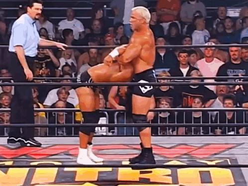 Two Men Are Wrestling In A Ring With The Word Nitro On The Floor GIF