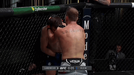 Two Men Are Wrestling In A Ufc Ring With A Howler Head Sign In The Background GIF