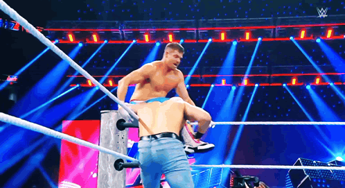 two men are wrestling in a wrestling ring on a stage with a lot of lights .