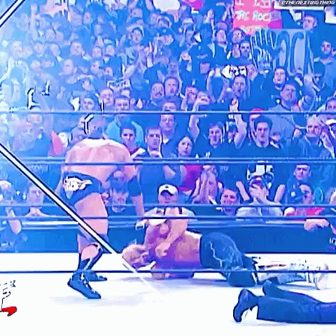 Two Men Are Wrestling In A Wrestling Ring With A Crowd Watching . GIF