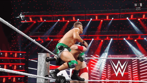 two men are wrestling in a wrestling ring with a w logo in the back