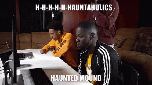 Two Men at Table With Haunted Mound Meme on Laptop