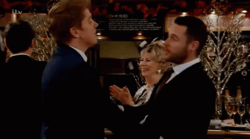 Two Men Beside ITV Sign GIF