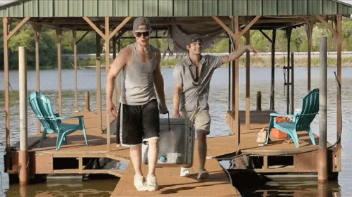 Two Men Carrying Cooler on Dock