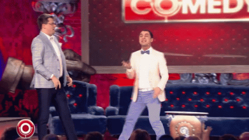 Two Men Dancing In Front Of Comedy Sign GIF