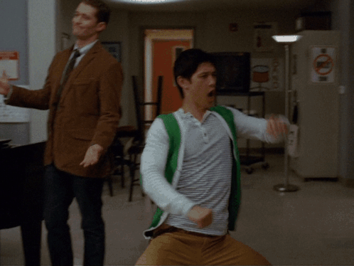 Two Men Dancing in Room With Recycle Sign