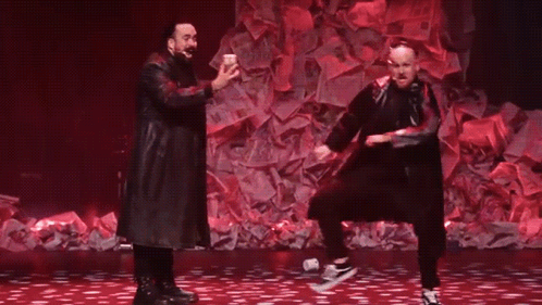 Two Men Dancing on Stage With Pile of Money