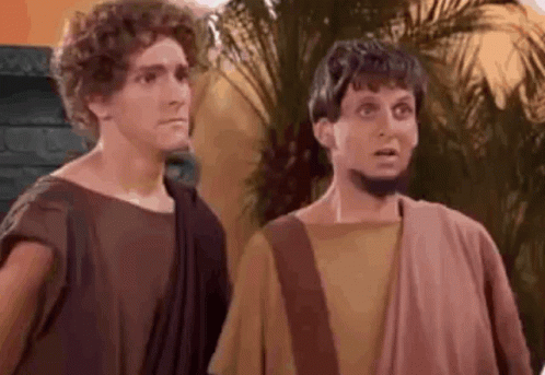 two men dressed as roman soldiers are standing next to each other and making funny faces .