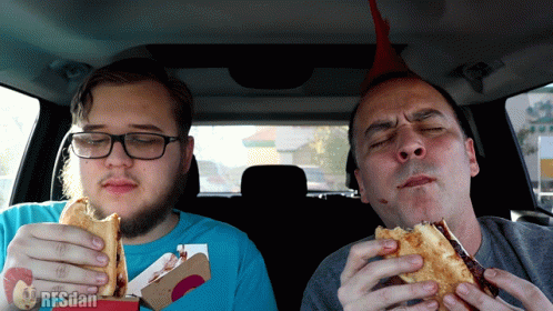 Two Men Eating Sandwiches in Car