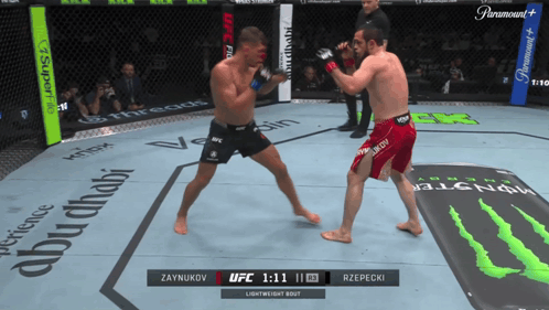Two Men Fighting in Boxing Ring With Monster Energy Mat
