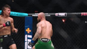 Two Men Fighting in Cage With Green Venum Shorts