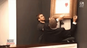 Two Men Hanging A Picture On A Wall With The Inside Edition Logo GIF