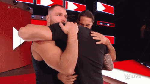 Two Men Hugging Each Other On A Red Carpet In Front Of A Red Wall . GIF