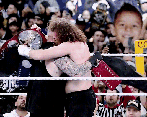 Two Men Hugging In A Wrestling Ring With A Sign That Says Cc On It GIF