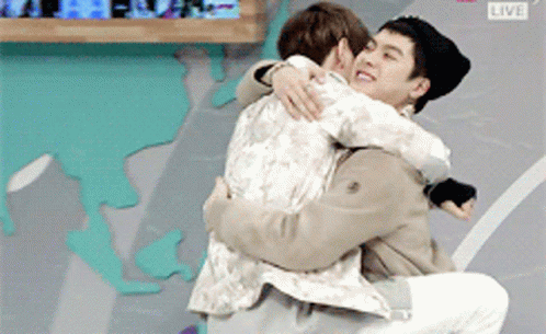 Two Men Hugging in Front of Live Screen