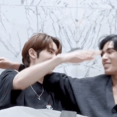 Two Men Hugging in Front of Marble Wall