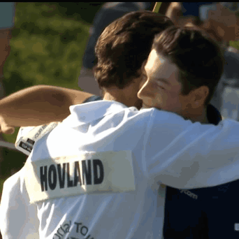 two men hugging with one wearing a shirt that says hovland on the back