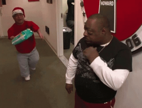 Two Men In A Hallway With A Sign That Says Howard GIF